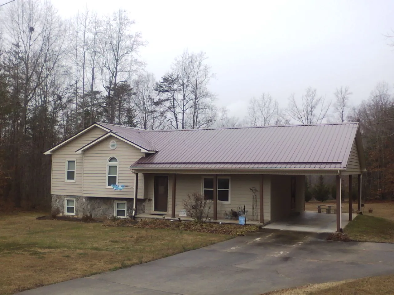 Burgundy metal roof on a tan split level home with an attached carport in Folly Beach