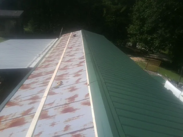 Old rusted panels beside newly installed green metal roofing — Wind Damage Roof Repair by Roofing Brothers in Folly Beach