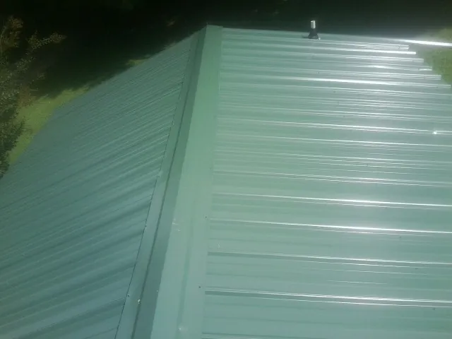 New green metal panels meeting at the ridge of a roof — Flat Roof Repair work by our crew in Folly Beach