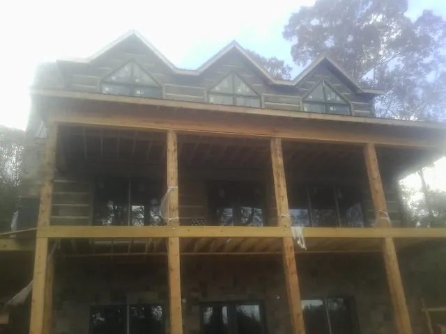 Dormers and porch framing on a large log home under construction — Roof Coating work by our crew in Folly Beach