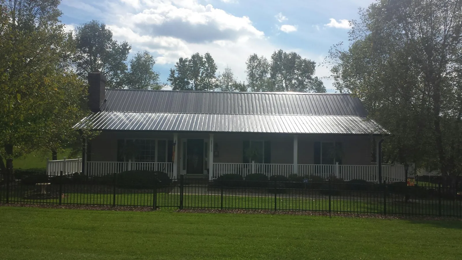 Gray metal roof on a brick ranch with a full width front porch — Gutter Guard Installation work by our crew in Folly Beach