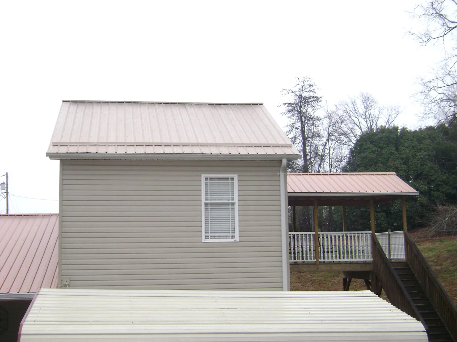 Tan metal roofs on a two story addition and attached porch, from a Roof Replacement job in Folly Beach