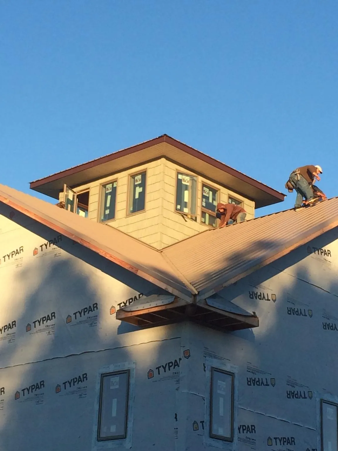 Roofers working around a rooftop cupola on a new metal roof at sunset — Roof Waterproofing in Folly Beach by Roofing Brothers